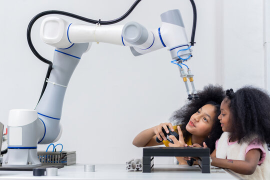 Kid female teen child enjoy Machine Learning Robot arm is Moving Under Control robot at technology class, stem education robot arms for digital automation software for artificial intelligence ai