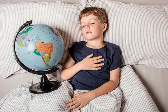 A young boy peacefully sleeping in bed while holding a globe, symbolizing childhood dreams, travel, geography, education, global unity, future exploration, and connection with the world.
