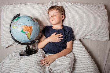A young boy peacefully sleeping in bed while holding a globe, symbolizing childhood dreams, travel, geography, education, global unity, future exploration, and connection with the world.
