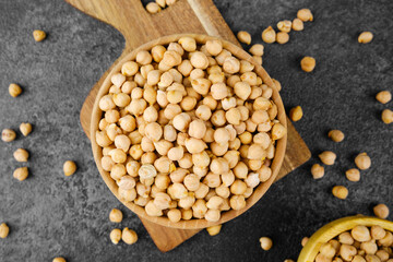 Yellow split peas in bowls on cutting board with scattered grains for rustic diet, legume protein or vegan meal concept