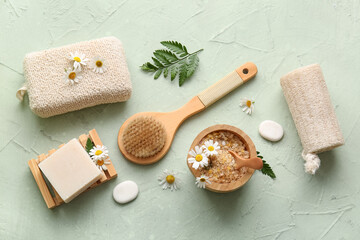 Obraz na płótnie Canvas Composition with soap bar, massage body brush, chamomile flowers and bowl with sea salt on green grunge background, closeup