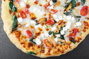 Closeup of pizza with melted cheese, tomatoes and spinach for fast food, menu or tasty lunch concept