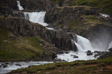 Majestic waterfall cascading over rocky cliffs into a river.