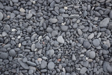 Evenly scattered pebbles on black beach