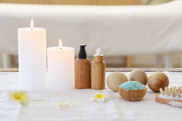 Composition with spa accessories, cosmetic products and tropical flowers on massage table in salon
