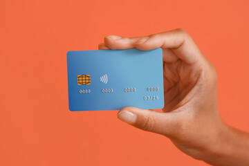Female hand with credit card on orange background