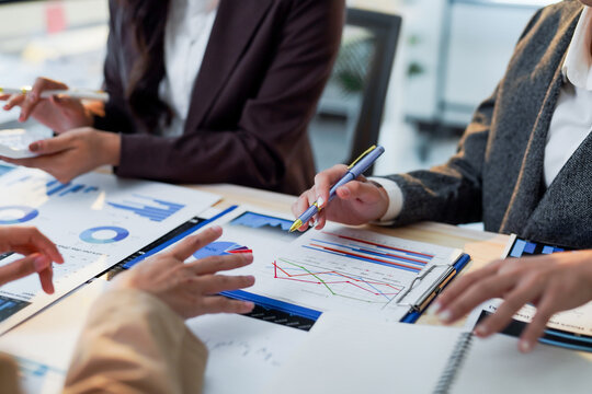 Business people discussing financial charts and graphs using calculator and pen during a meeting