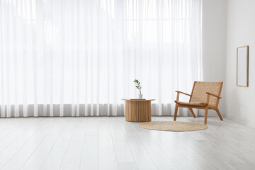 Interior of living room with light curtain, wooden armchair and table