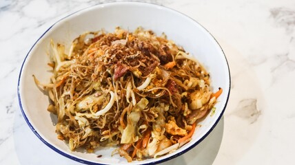 close up of stir fried Singaporean Hokkien Mee or called fujian noodles which is thick egg noodles in dark soy sauce, pork rind, shrimp, sliced fish, squid and sliced pork