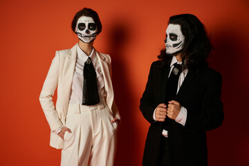 Couple honours dia de los muertos with sugar skull faces and elegant attire