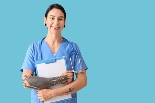 Tattooed female doctor with clipboard on blue background - Powered by Adobe