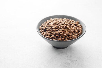 Side view of full bowl with dry dog food kibbles on white background