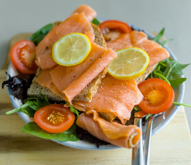 Close-up View of Healthy Diet Omega-3 Smoked Salmon, Salad with Lemon and Sourdough Bread on Wood Board