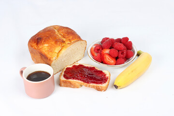 French breakfast with brioche bread, jam, and fresh fruits on a white background