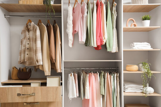 Wardrobe with shelves, drawer and clothes in room - Powered by Adobe