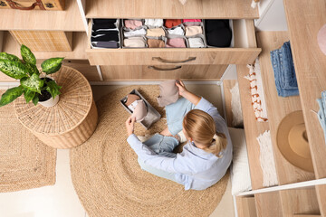 Young woman with bras and organizer sitting in wardrobe, top view