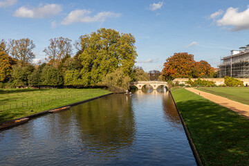 Cambridge, England. Gardens and walkways of King's College with autumn foliage, the River Cam, and punts moored along the riverbank beside the historic college grounds