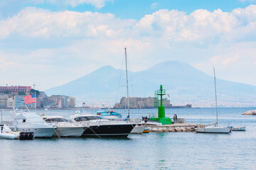 Obraz premium View from Molo di sopraflutto Sannazzaro also called Molo Luise marina in Naples, Italy. Yachts and other boats are moored in the harbor, with the cityscape and Mount Vesuvius