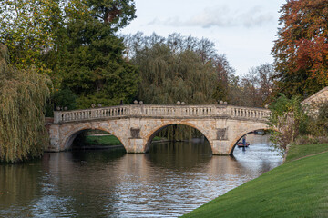 Fototapeta premium Cambridge, England. Clare Bridge, the oldest surviving bridge over the River Cam built in 1640, with autumn foliage and reflections on the water near King's College gardens