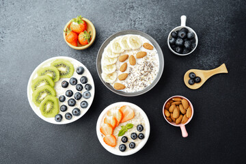 Assorted breakfast oatmeal bowls with fruits chia seeds and almonds on black background