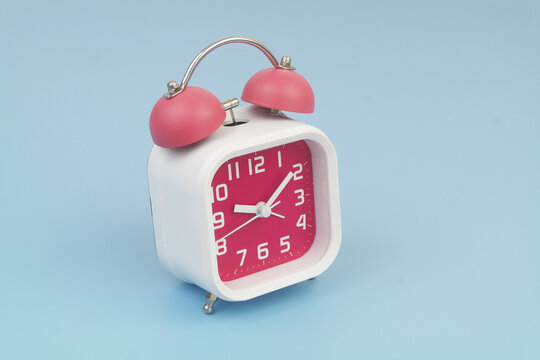 Red and white alarm clock on blue background. Copy space for text.