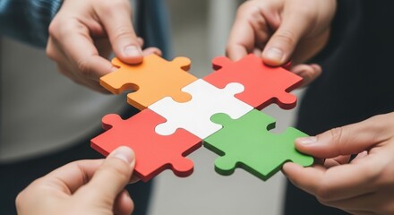 Four hands coming together to connect colorful puzzle pieces in a collaborative effort indoors