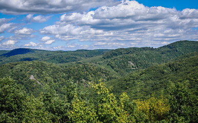 Obraz premium Panoramic view of endless green forested hills under a partly cloudy sky, captured from the vantage point of Őr-parlag in the Bükk Mountains, Hungary.