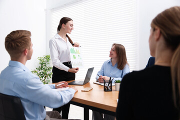 Business coach giving presentation to group of people in office