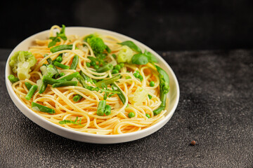 Spaghetti vegetables green peas, broccoli, string beans, kohlrabi vegetarian pasta tasty snack fresh delicious gourmet food background on the table rustic top view copy space vegan food