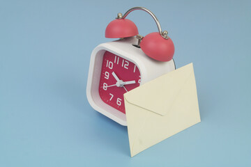 Envelope ad alarm clock on blue background, shipping and mail delivery time concept.  