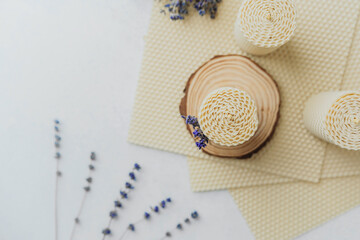 Beeswax candle on wood slice with lavender bouquet and wax sheets
