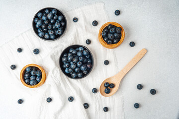 Fresh blueberries arranged on a cloth with bowls and a wooden spoon