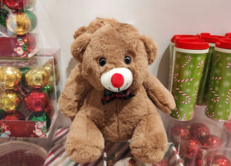 A soft brown teddy bear toy in a shop window. A holiday card for the New Year holiday.