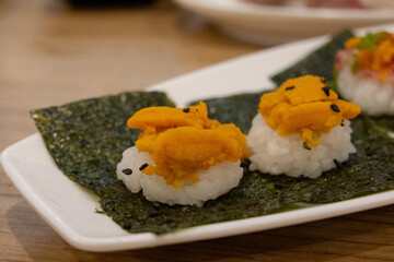 close-up of uni (sea urchin roe) on balls of sushi rice, wrapped in sheets of nori seaweed