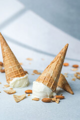 Vanilla ice cream cones with almonds on light surface