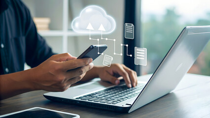 Businessman works with smartphone and laptop, interacting with a translucent cloud icon floating above the devices
