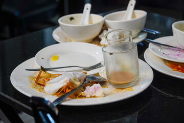 Discarded dishes on a table present a scene of culinary aftermath. The plates and bowls, once filled with food, now bear the remnants of a meal, conveying a sense of completion and the end of a feast.