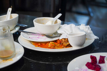 A still life photograph showing the remains of a meal, emphasizing the remnants of food and used tableware, capturing a sense of ephemerality and the transient nature of dining.