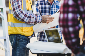 Construction workers are discussing blueprints on a job site, teamwork and project planning in the construction industry.