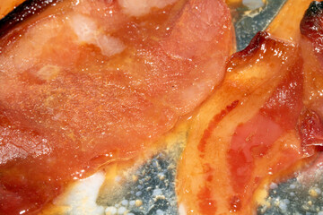 Close up of freshly grilled slightly burnt bacon strips on tin foil