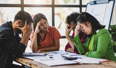Stressed business people having headache during meeting in office. Stressed colleagues in office facing challenges, feeling tired and overwhelmed.