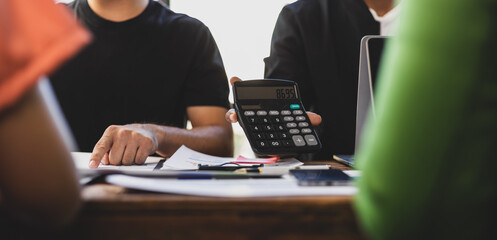 Business people analyzing financial documents and discussing start up strategy during a meeting at office desk.