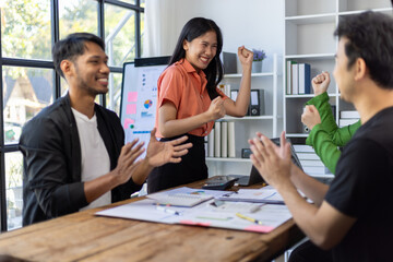 Excited business team celebrating successful startup project in office meeting.