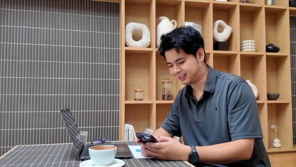 A man is sitting at a table with a laptop and a cell phone