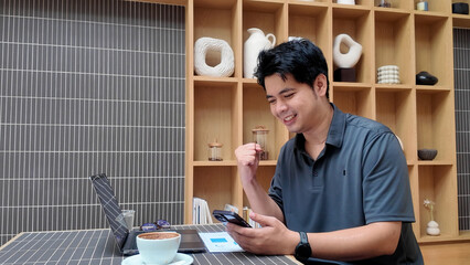 A man is sitting at a table with a laptop and a cell phone
