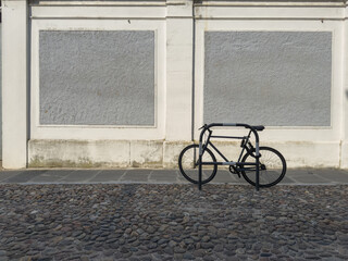 Dark bicycle leaning against a railing