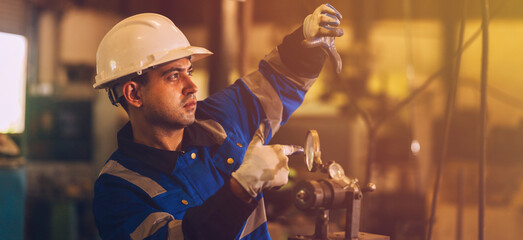 A male mechanical engineer is inspecting work in a steel lathe factory.