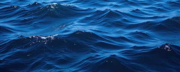 Close up of deep blue ocean waves with sunlight reflecting on the water's surface
