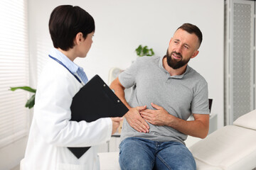Obraz premium Gastroenterologist consulting patient with stomach pain in clinic