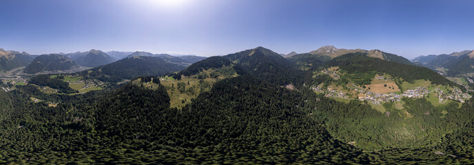 Super wide angle aerial panorama of mountain slope with green meadows and pine tree divide with cloud obscuring half of the scenery. Picturesque colorful high altitude weather condition concept.